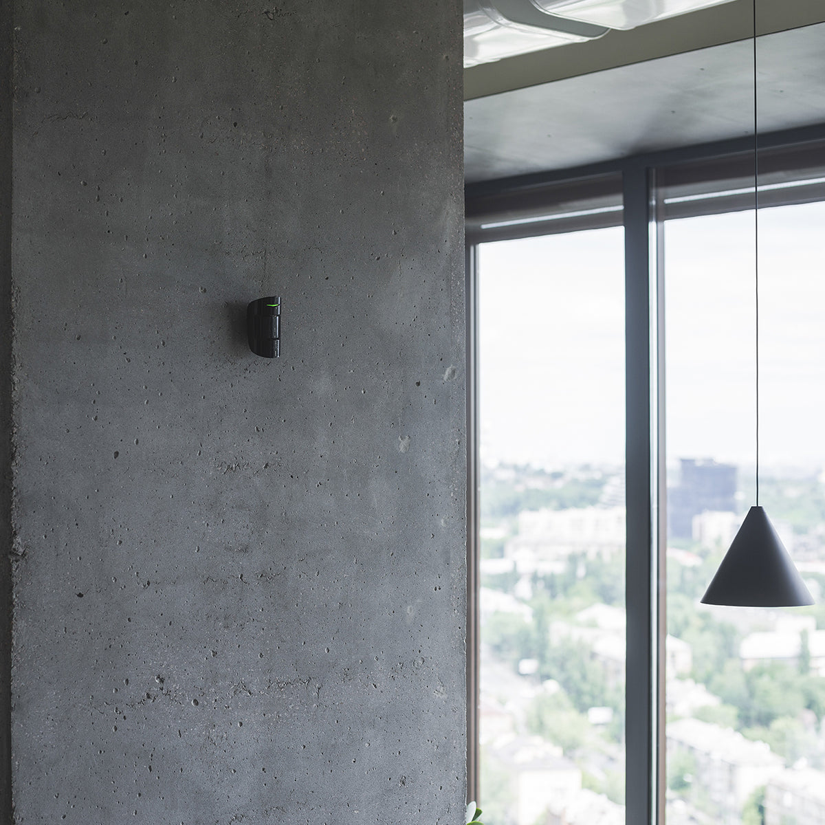 Ajax CombiProtect wireless indoor motion and glass break sensor in black installed on wall.