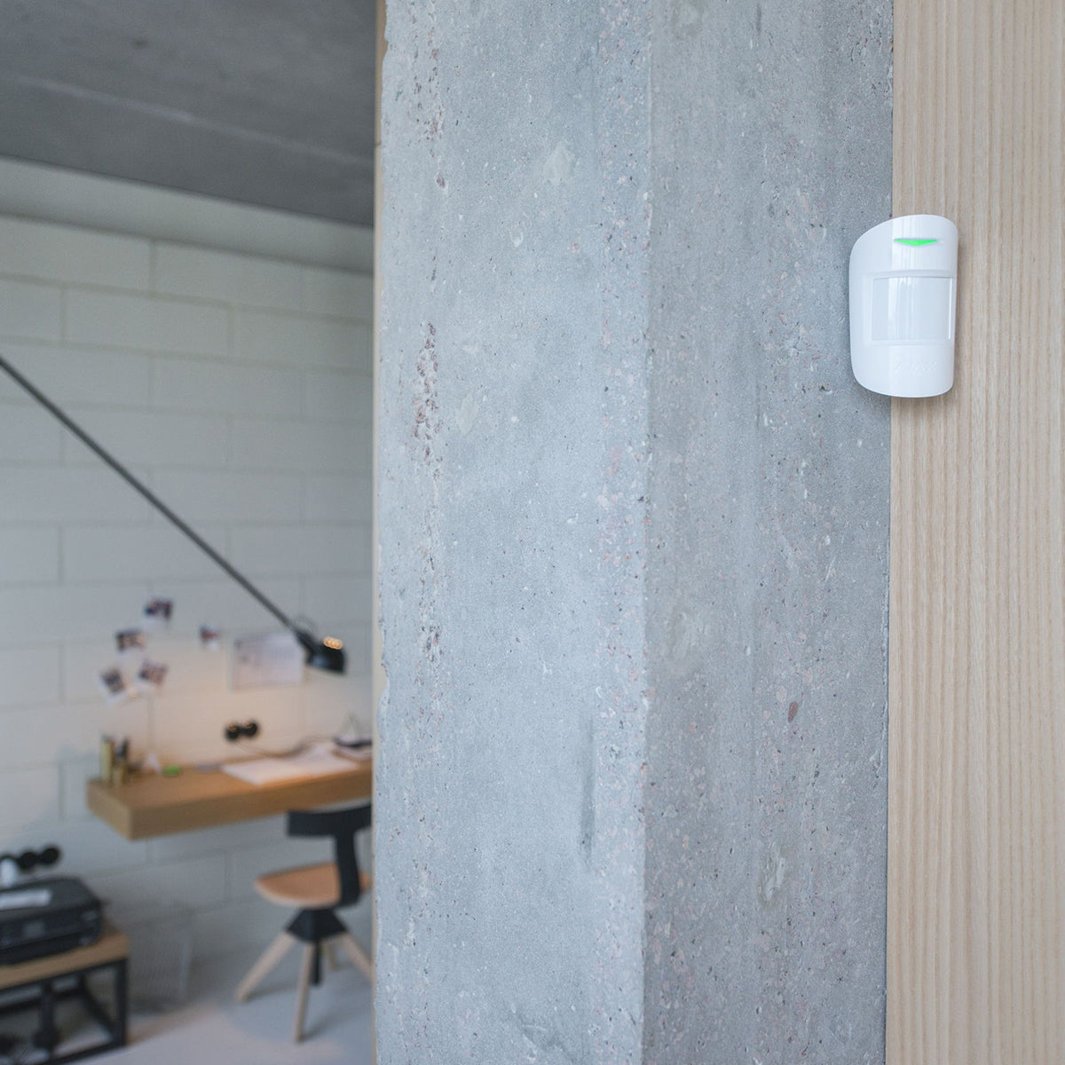 Ajax Wireless indoor motion sensor installed on wall for smart security monitoring.
