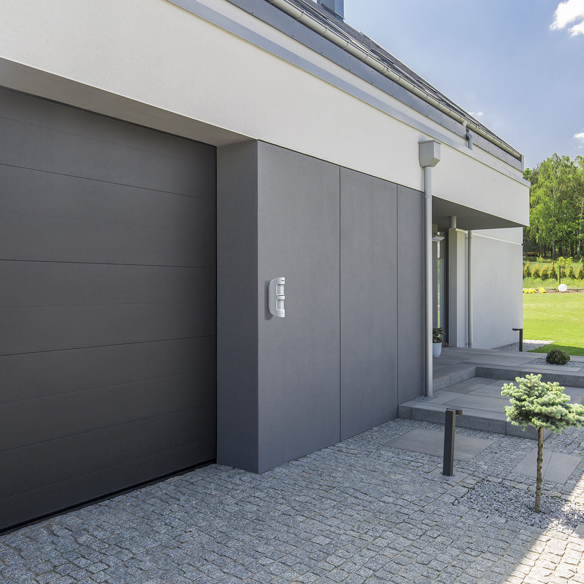 Ajax wireless MotionProtect outdoor sensor in white mounted beside a garage for reliable perimeter home security.