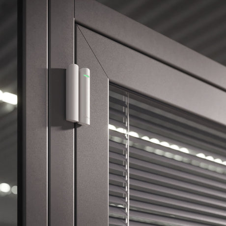 Ajax wireless DoorProtect opening detector in white, mounted on a door frame for reliable smart home security.