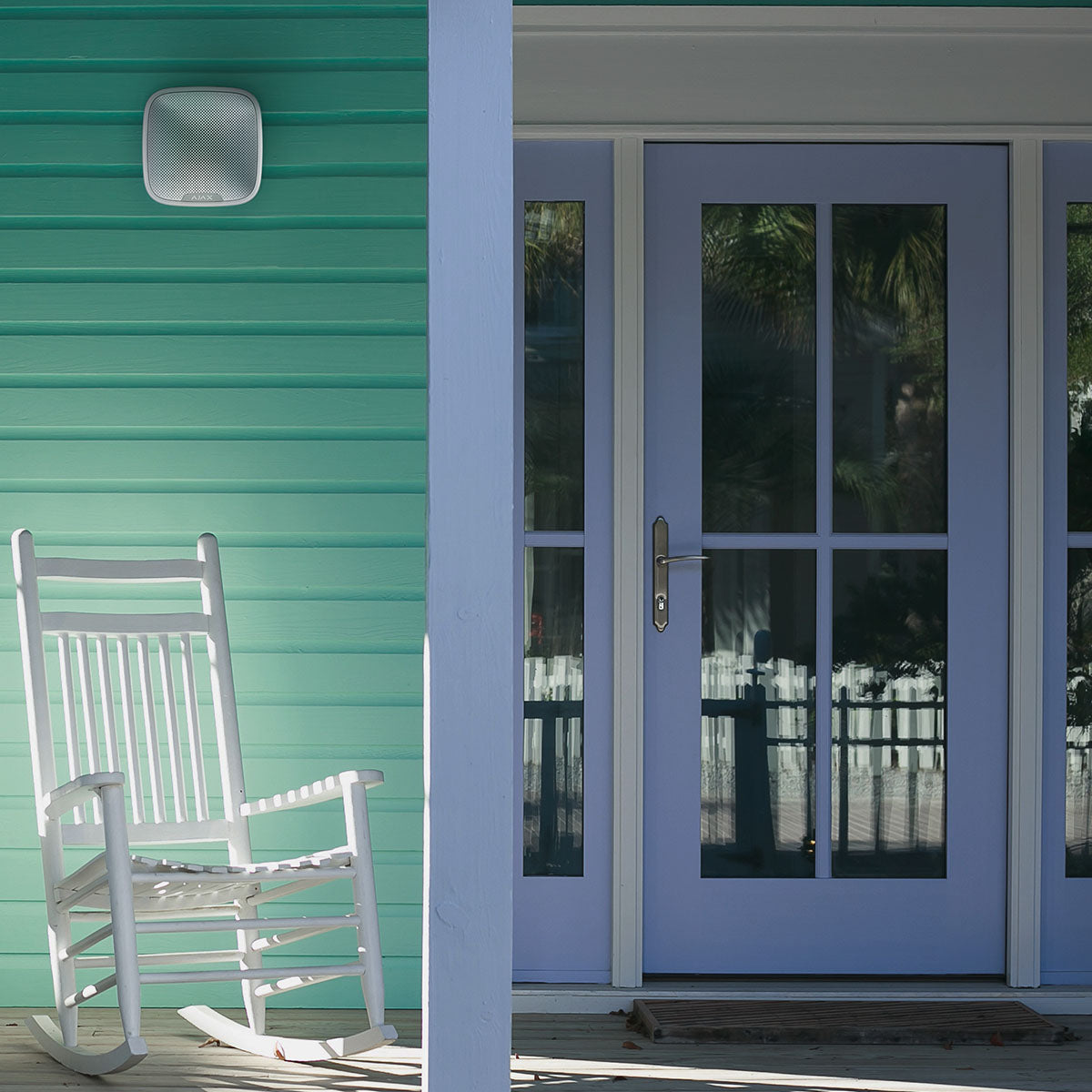 Ajax wireless outdoor 113dB white StreetSiren mounted on the exterior, shown in a lifestyle setting near a front door.